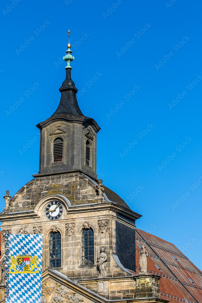 Spitalkirche in Bayreuth mit Flagge Bayerns vor blauem Himmel