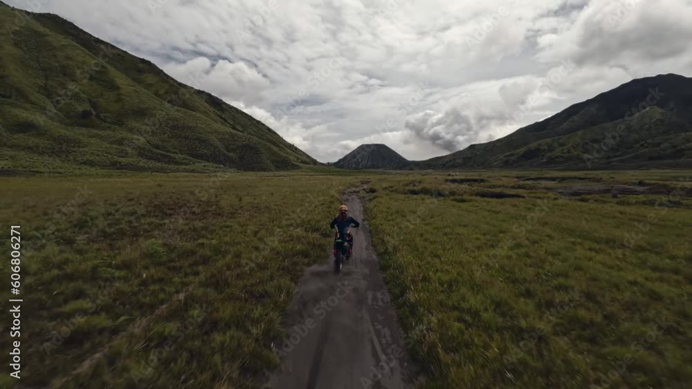 Aerial view biker riding on moto enduro path between volcano mountain landscape extreme adventure. FPV drone follow shot motorbike motocross speed racing power race trip at rock scenery cloudy sky 4k Aerial view biker riding on moto enduro path between volcano mountain landscape extreme adventure. FPV drone follow shot motorbike motocross speed racing power race trip at rock scenery cloudy sky 4k