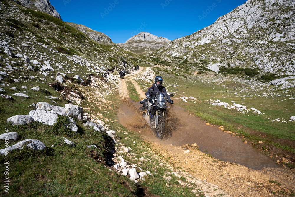 Young man wearing body armour riding through a deep puddle on the Trans Euro Tra il in Montenegro