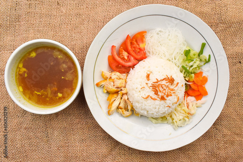 Indonesian chicken soto or soto ayam, served with white rice, vermicelli noodles, shredded chicken, bean sprouts, cabbage, carrots, tomatoes, and fried shallots.