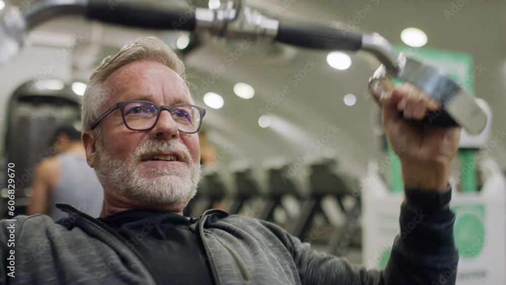 Senior man in his 60s working out at the gym on a lateral pulldown pulley machine Senior man in his 60s working out at the gym on a lateral pulldown pulley machine