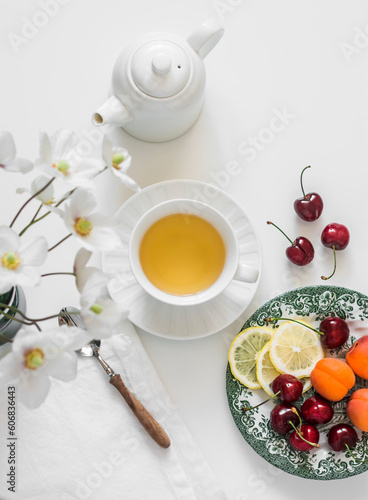 Green tea, summer seasonal fruits and berries on a light background. Delicious healthy snack