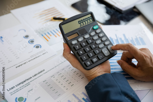 Close up of a man's hand using a calculator Business analysis, investment and finance concept. Businessman, accountant calculating business report. market information Financial graph while working on 