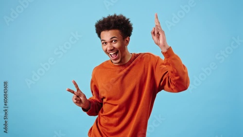Positive young man winks and dances making funny movements photo