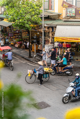 People, vendors, bicycles and cyclo drivers taking tourist on a busy, bustling street in the old town of Hanoi, in northern Vietnam. Famous destination of Vietnam