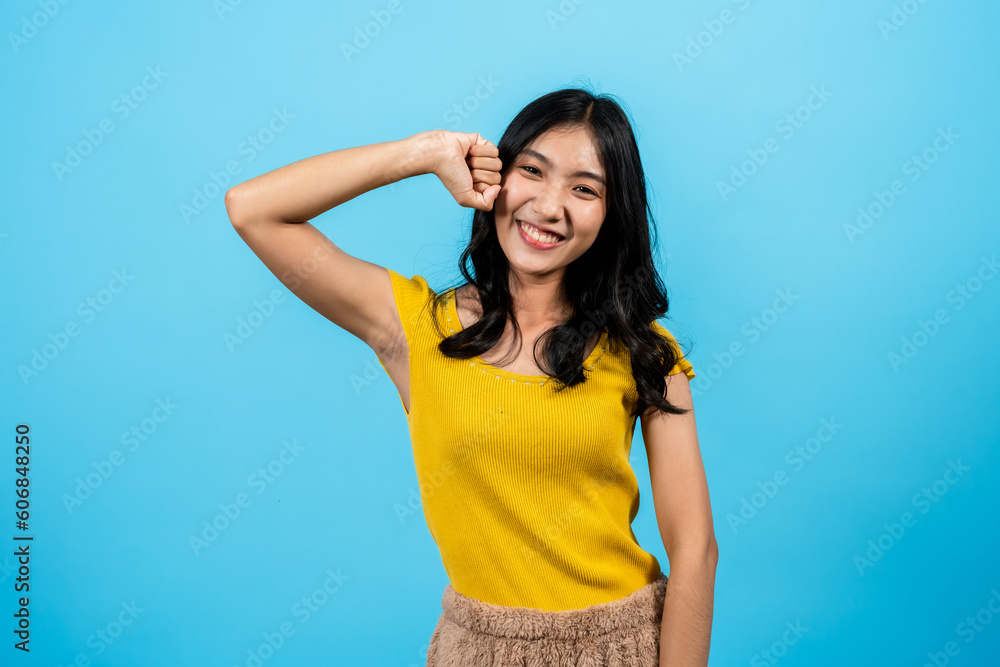 Portrait, asian girl long hair wearing fitted shirt, stand smile make pleading face, clenched fist lifted up side head with cute tilt head, Isolated indoor studio on blue background. Portrait, asian girl long hair wearing fitted shirt, stand smile make pleading face, clenched fist lifted up side head with cute tilt head, Isolated indoor studio on blue background.