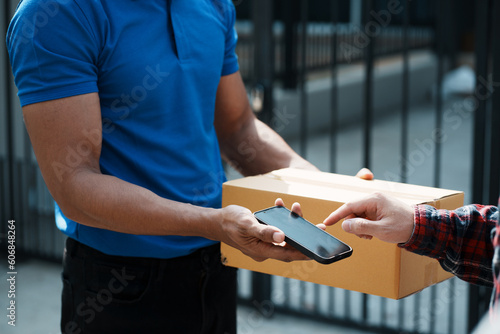 Delivery man handing parcel box to customer, percel box being paid with contactless nfc payment with phone.