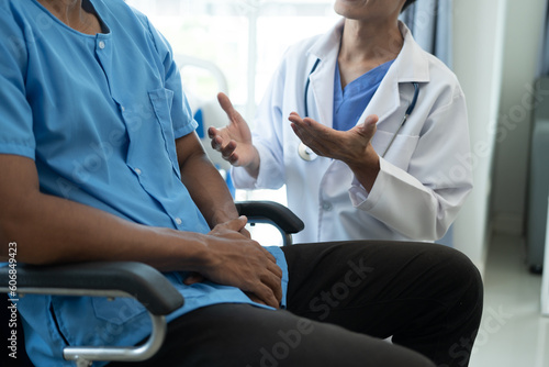 Friendly Male Doctor Talks to Male Patient. doctor with chart attending sick man in hospital ward.