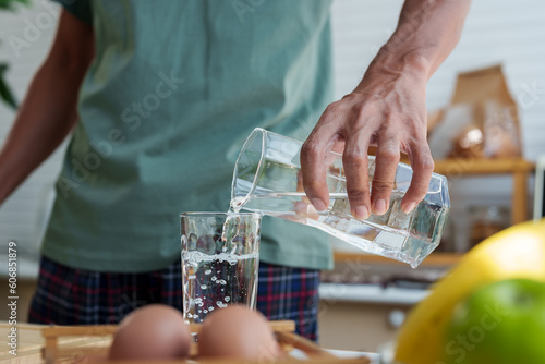 Close-up shot of Asian man's hand Pouring water from the gums into a glass to drink on the morning of the holiday after breakfast Fototapet