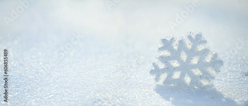 Christmas winter background, banner - view of a decorative snowflake on snow sparkling in the rays of the sun, selective focus, copy space for text © rustamank