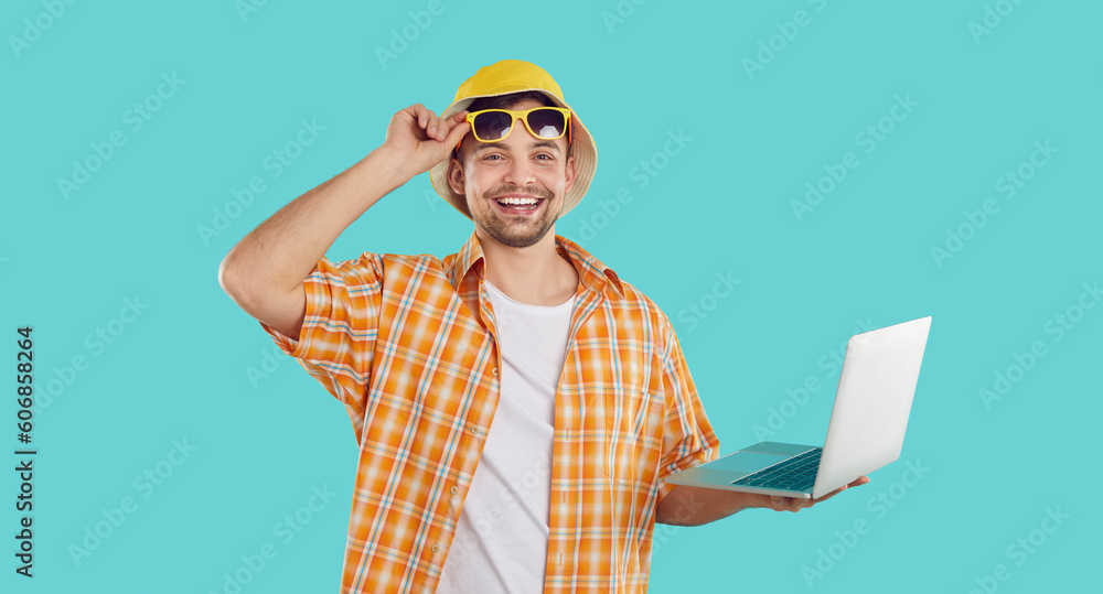 Happy funny cheerful handsome young man going on summer holiday, using modern laptop computer, booking tickets online, and browsing best prices on travel agency website. Traveling, vacation concept Happy funny cheerful handsome young man going on summer holiday, using modern laptop computer, booking tickets online, and browsing best prices on travel agency website. Traveling, vacation concept