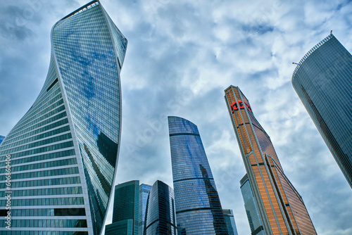 Glass skyscrapers of Moscow City against a cloudy sky.