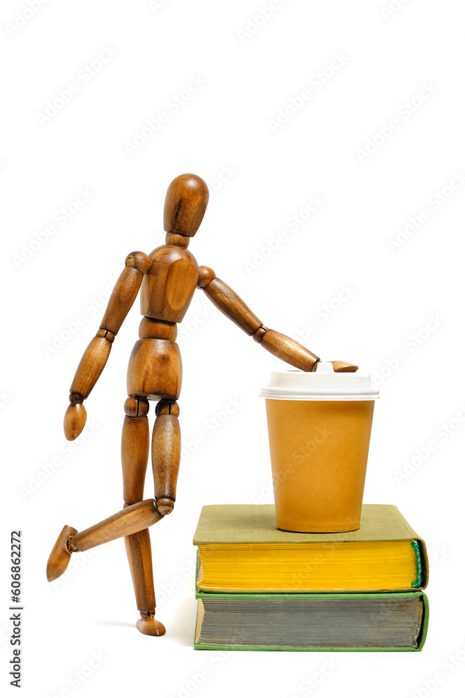 Wooden brown mannequin stands next books and glass of coffee.Concept reading books. Wooden brown mannequin stands next books and glass of coffee.Concept reading books.