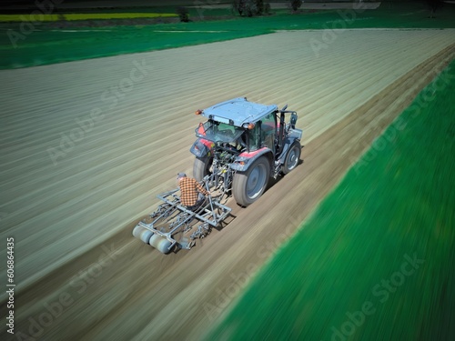 traktor orający pole. Zdjęcie z rozmyciem ruchu. Na pługu siedzi rolnik