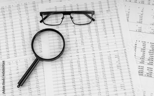 Magnifying glass and eye glasses on financial statement.
