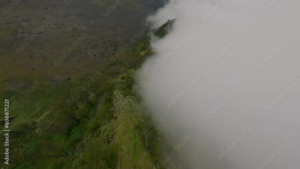 Aerial view flying over natural Asian volcano crater ridge geology formation smoke and lava field. FPV sport drone shot picturesque mountain wild valley hilly terrain danger volcanic eruption mist fog Aerial view flying over natural Asian volcano crater ridge geology formation smoke and lava field. FPV sport drone shot picturesque mountain wild valley hilly terrain danger volcanic eruption mist fog