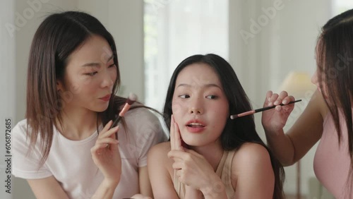 beautiful Asian women have a fun time applying blush on friend cheeks