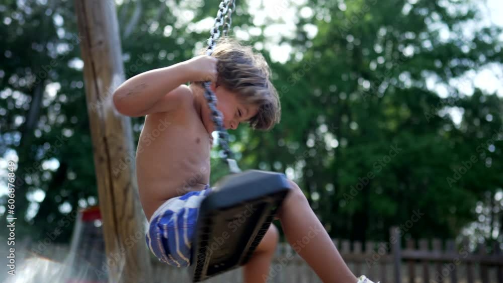 One small boy having fun at playground swing outdoors during summer day shirtless kid. Child spinning outside having fun One small boy having fun at playground swing outdoors during summer day shirtless kid. Child spinning outside having fun