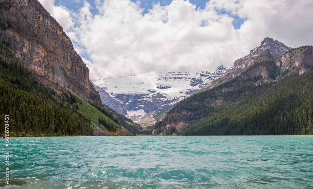 Lake Louise in Banff National Park, Alberta, Canada. Lake Louise panorama of snow-capped mountain peaks, coniferous forest and blue glacial lake, cloudy day. concept - mountain tourism. copy space 