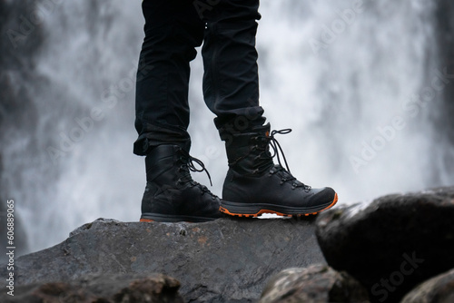 Mountain boots in front of a waterfall
