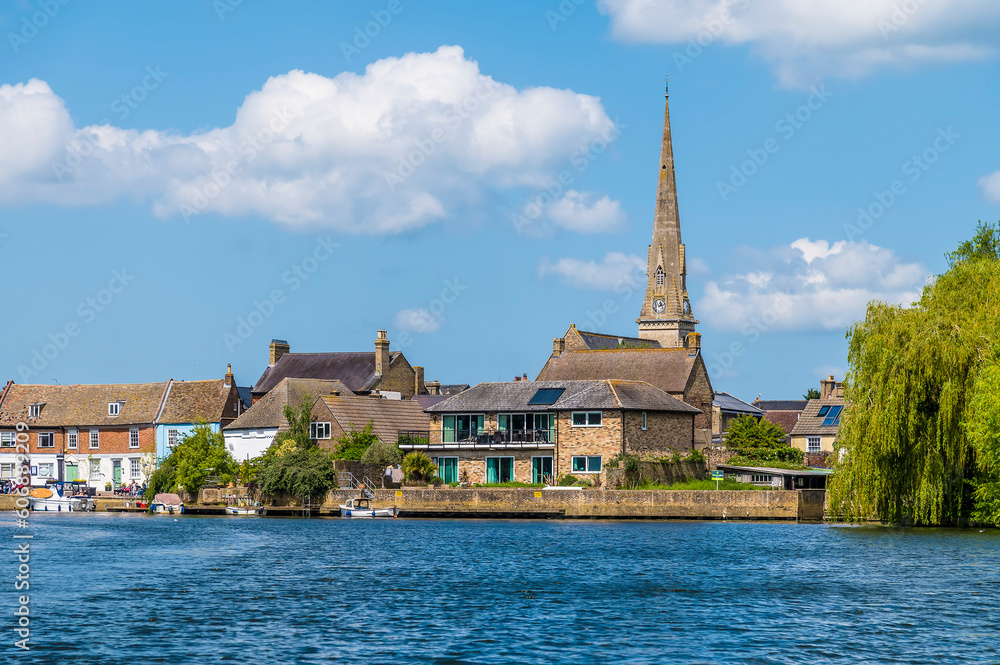 A view from the River Great Ouse towards the shore and church at St Ives, Cambridgeshire in summertime