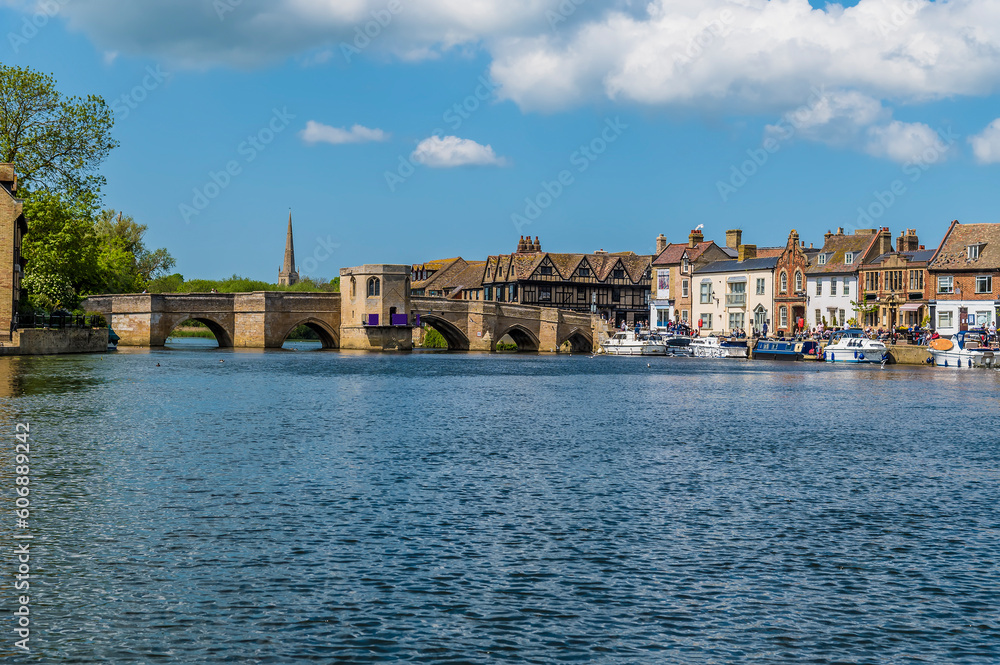 A view westward on the River Great Ouse towards the shore and footbridge at St Ives, Cambridgeshire in summertime