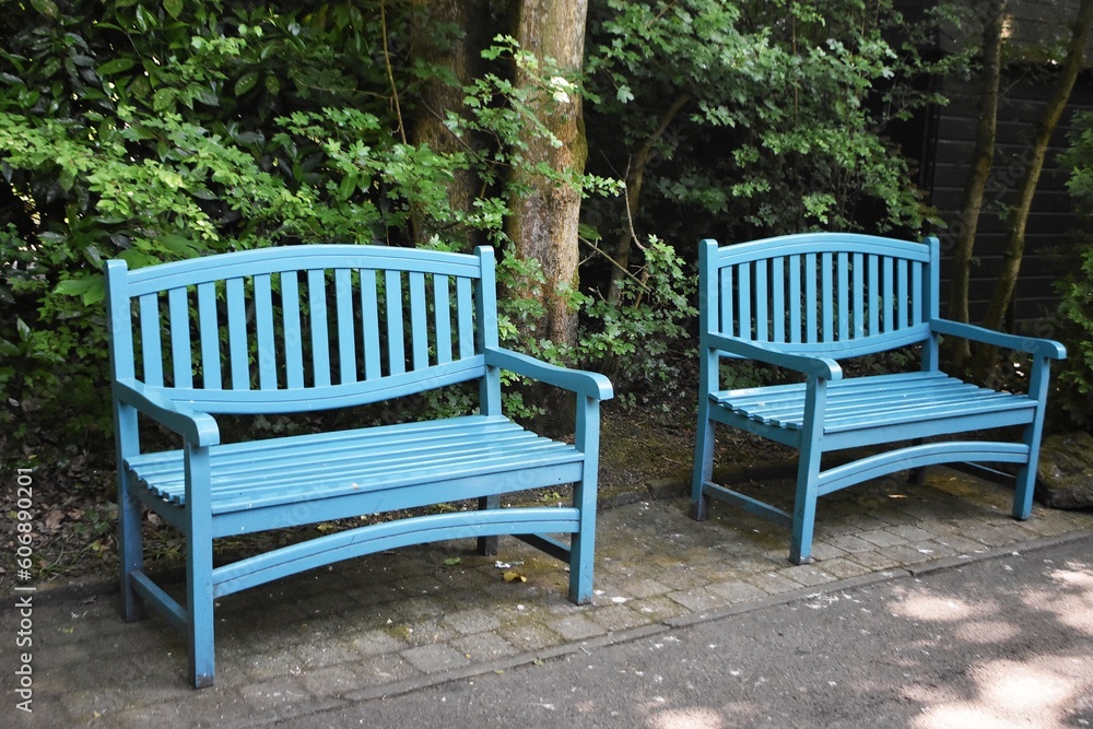 Blue wooden benches in the garden on a sunny summer day. A place for rest and relaxation. Blue wooden benches in the garden on a sunny summer day. A place for rest and relaxation.