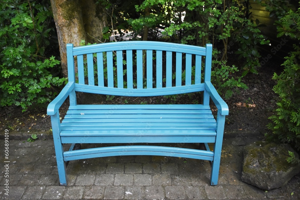 A blue wooden benche in the garden on a sunny summer day. A place for rest and relaxation. A blue wooden benche in the garden on a sunny summer day. A place for rest and relaxation.