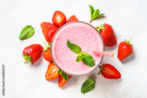 Strawberry smoothie or milkshake in glass at white table. Top view.