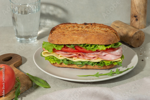 Sandwich with mortadella, cheese and tomatoes on a gray table