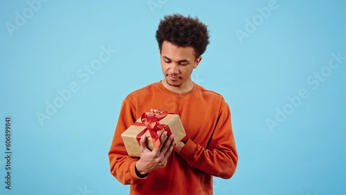 Happy African American man examines gift box with red bow photo