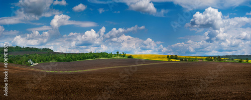 agricultural landscape, plowed field in the foreground, lines of fields and h...