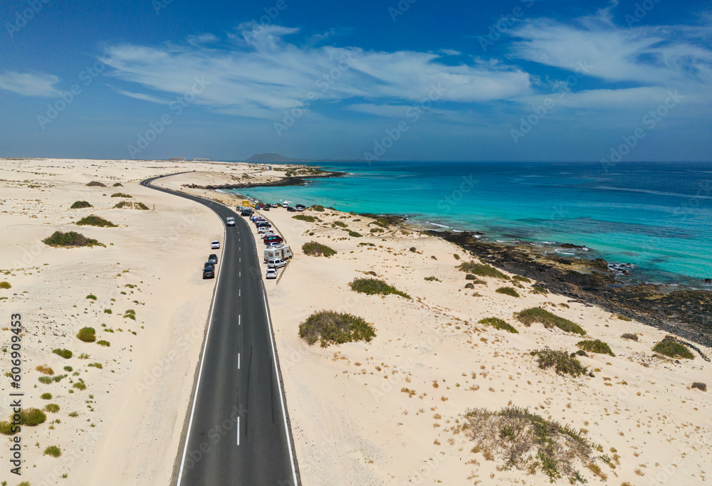 Aerial mid level panoramic view of Moro Beach and the road between the coast and Parque Natural sand dunes heading to Corralejo Fuerteventura Spain