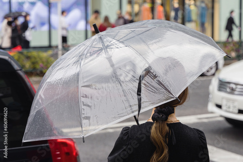Woman with umbrella waits at the street to cross