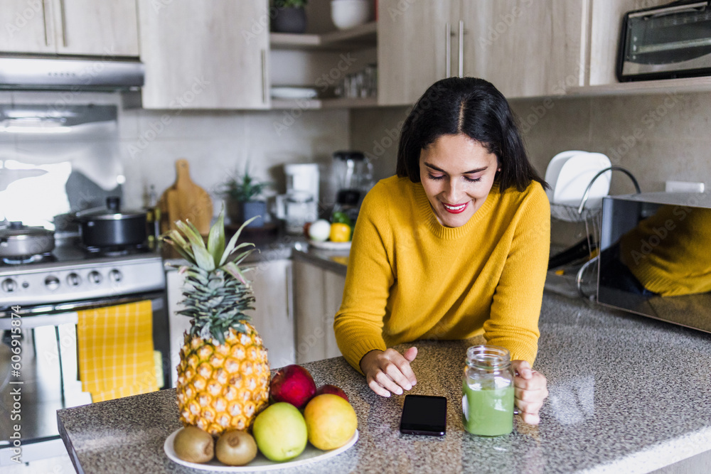 Φωτογραφία Latin adult woman drinking detox drink or green juice in kitchen at home in Mexi