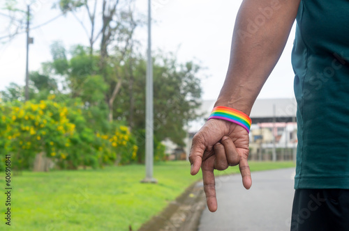 Hand wearing rainbow or lgbtq+ symbol wristband stretching down with  love symbol to campaign for protection and support on gender diversity or lgbtq+ people and community © nathamag11