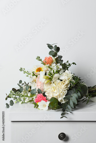 Fototapeta Naklejka Na Ścianę i Meble -  Bouquet with beautiful flowers on chest of drawers near white wall