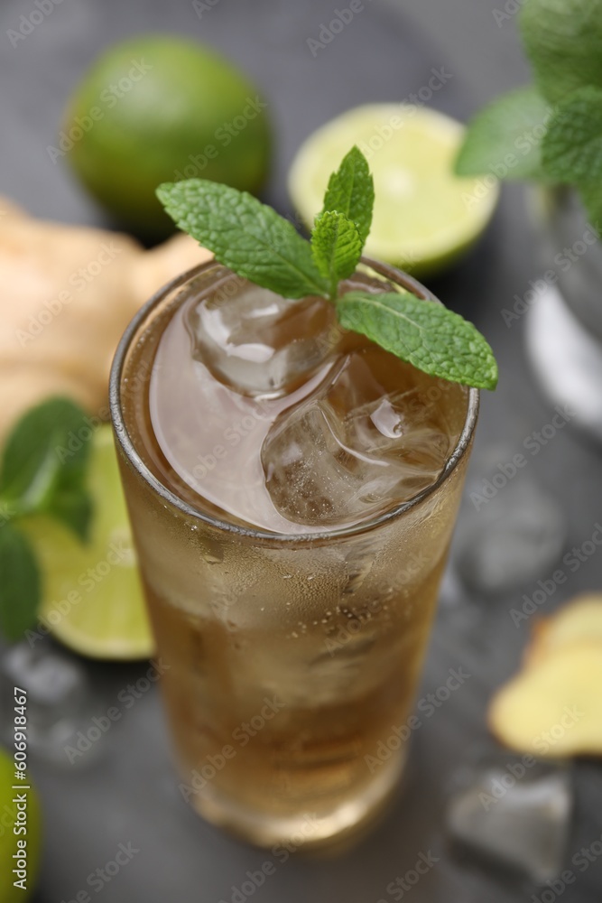 Glass of tasty ginger ale with ice cubes and mint on grey wooden table, closeup Glass of tasty ginger ale with ice cubes and mint on grey wooden table, closeup