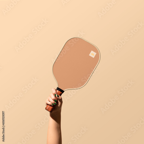 Female Hand Holding Pickleball Paddle on solid backdrop photo