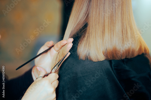 Hairdresser Hands Holding Scissors and Comb Cutting Hair Straight. Hairstylist cutting the split ends of a little girl 