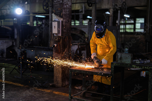 Welder with Torch Protective Helmet and leather suit in big hall welding metal and fire spark  © Tongpool