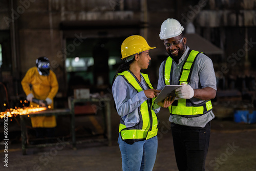 Engineer and manager look at tablet checking the maintenance part while the welder welding sparking 