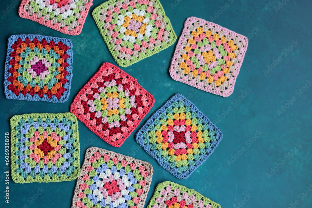 Granny squares on blue background. Top view with copy space. Handmade crocheting, needlework and handicraft concept - crocheting accessories