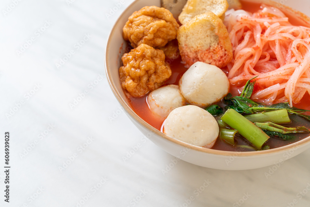 small flat rice noodles with fish balls and shrimp balls in pink soup