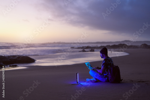 side view silhouette mature digital nomad man sitting on the beach shore working on his laptop at sunset