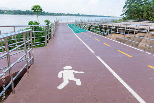 There are 2 bicycle roads next to the river. The pedestrian and bicycle lanes have the symbols of people and bicycles.