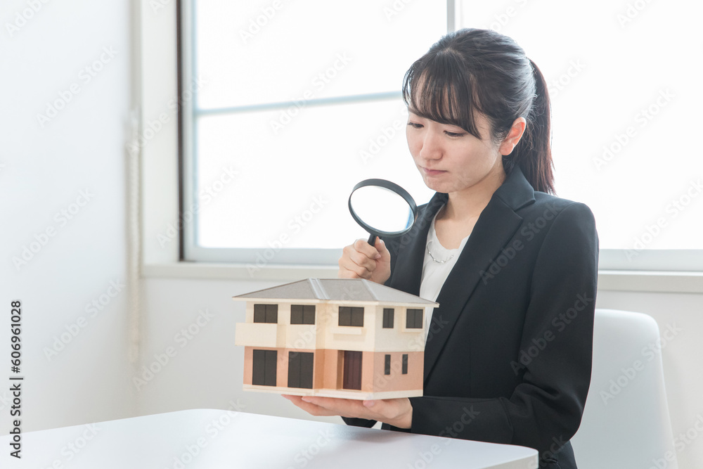 Φωτογραφία 虫眼鏡で模型の家を見る困る・悩む不動産業者の女性