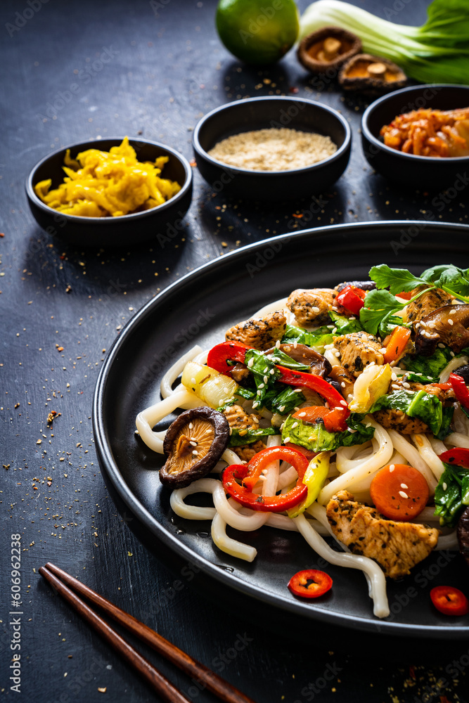 Chicken nuggets with noodles and stir fried vegetables on black table

