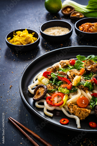 Chicken nuggets with noodles and stir fried vegetables on black table

