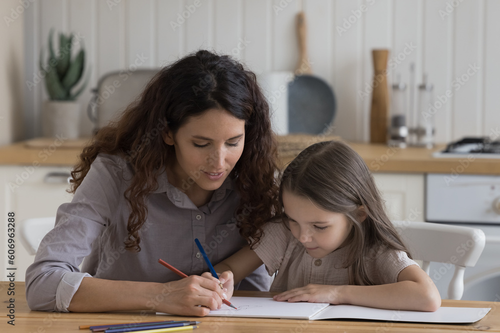 Φωτογραφία Focused positive mom and cute little girl kid drawing in colorful pencils togeth